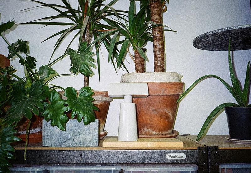   The Caret portable light ﻿by Mateo Fogale for ﻿&tradition in silk grey displayed with some plants.